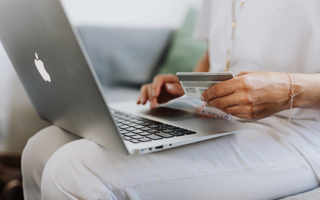 person using a macbook and holding a credit card